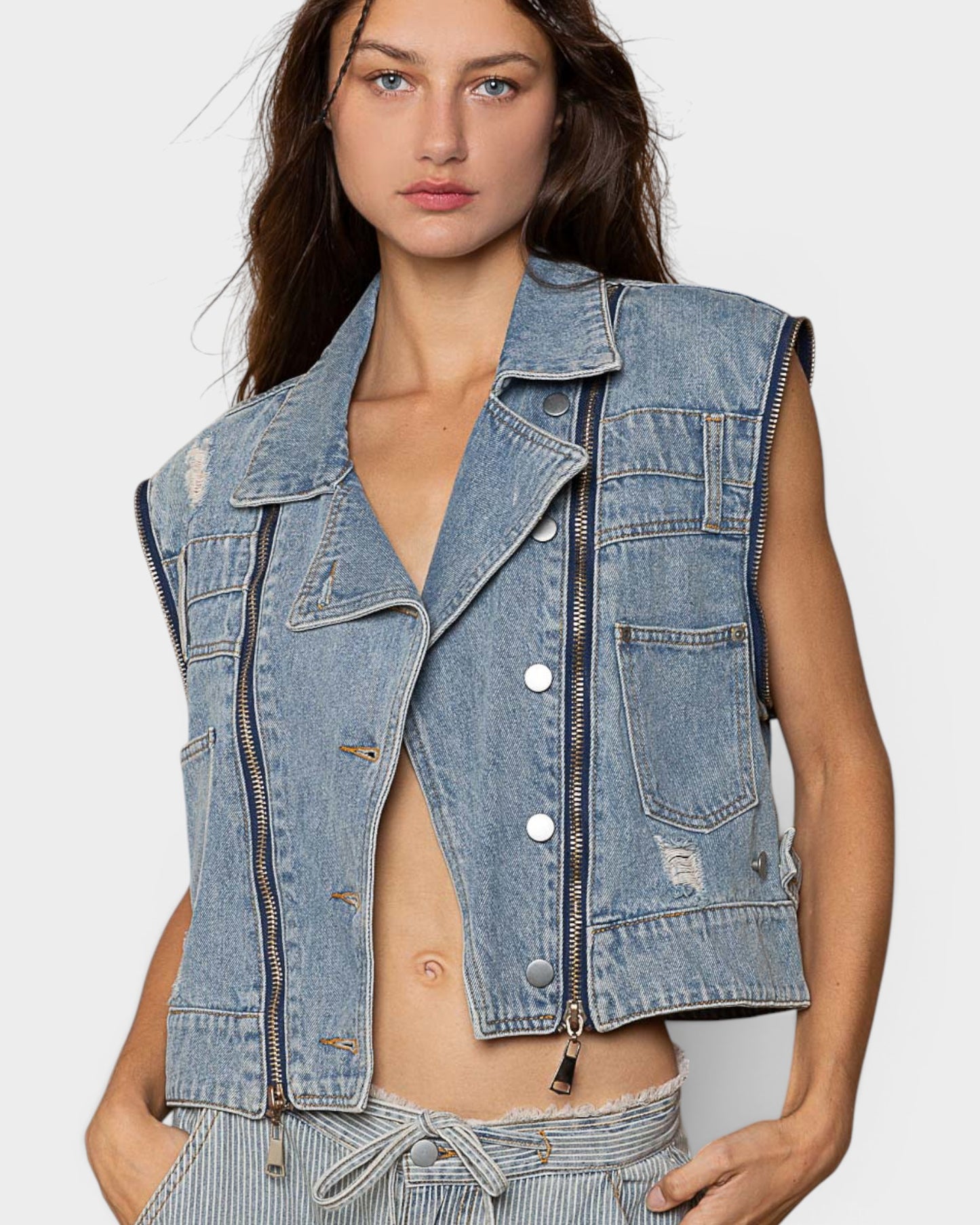 Woman wearing a denim vest on a plain background
