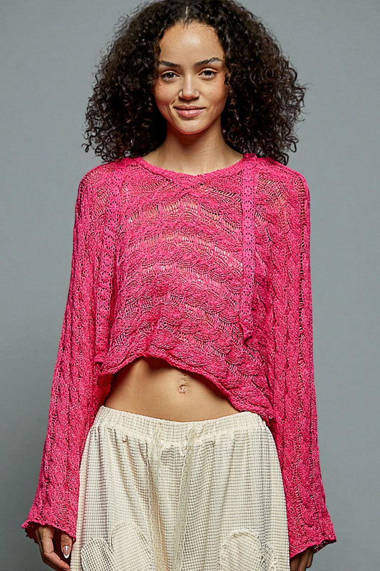 Woman wearing a bright pink knitted top against a gray background