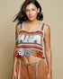 Woman wearing a colorful, patterned tank top against a beige background