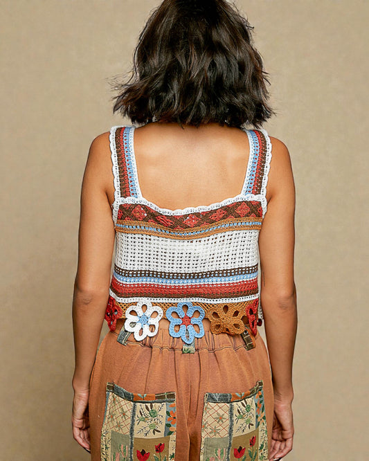Person wearing a colorful crochet top with floral details on a beige background