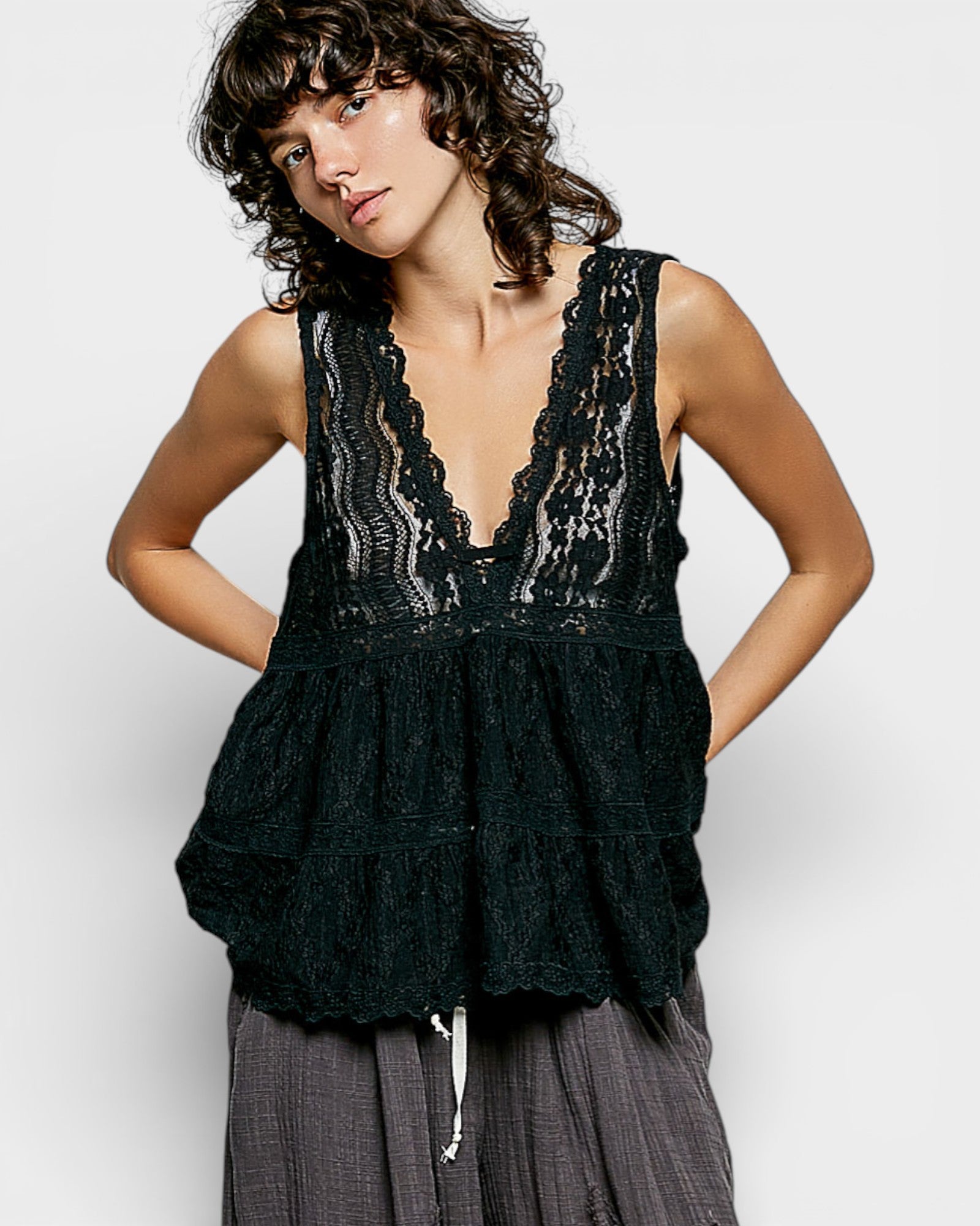 Woman wearing a black lace top with a plain background