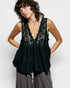 Woman wearing a black lace top with a plain background
