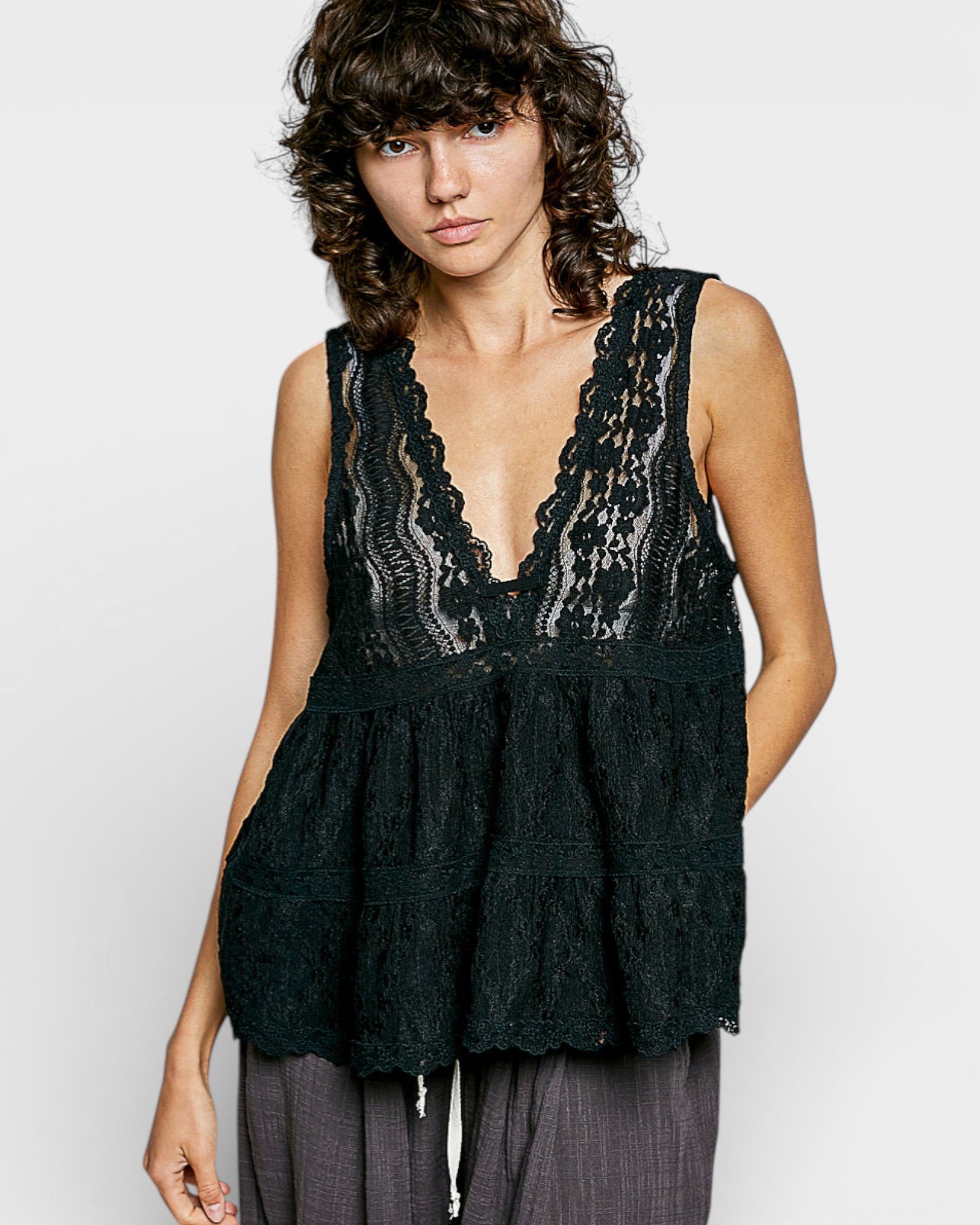 Woman wearing a black lace sleeveless top against a white background