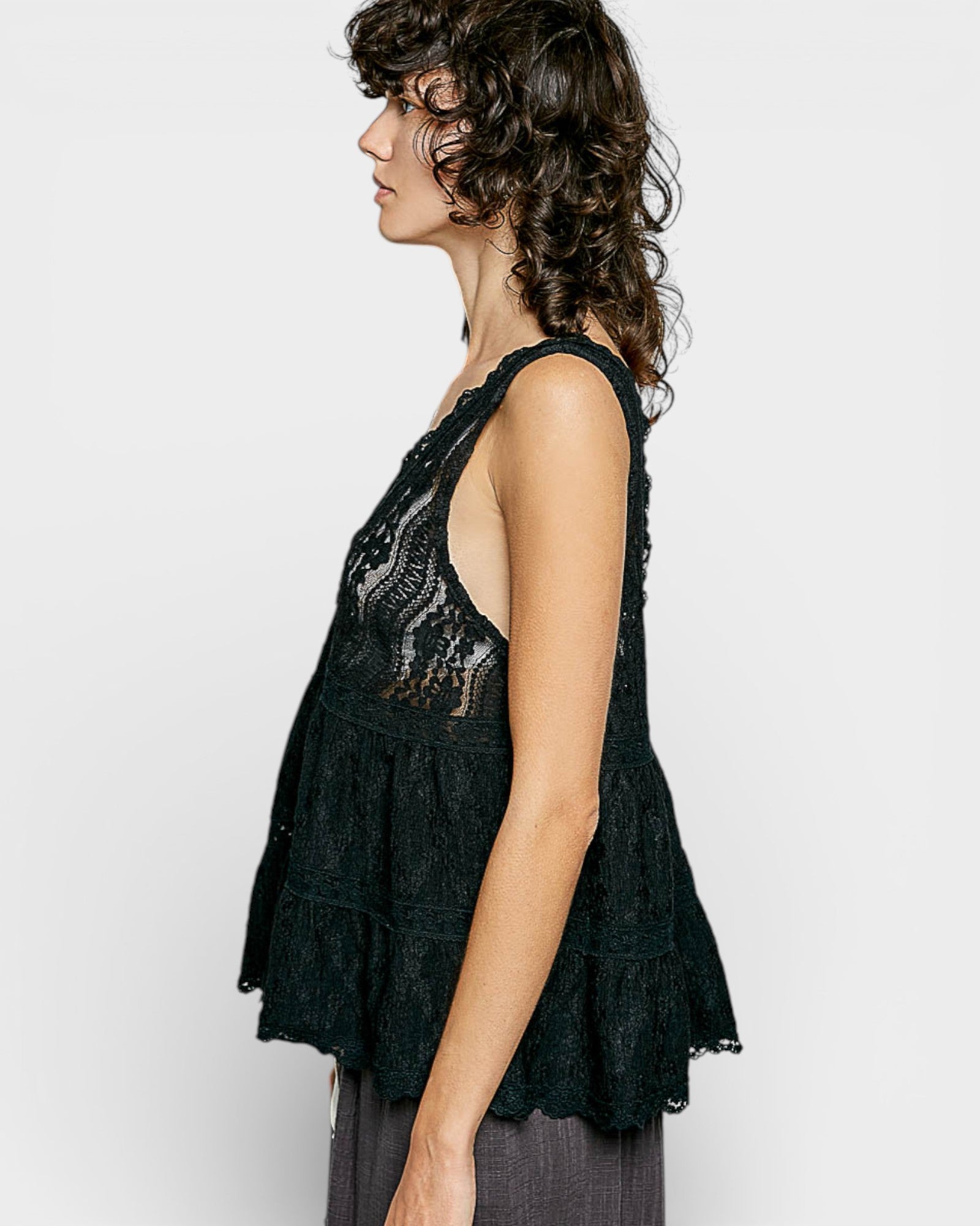 Woman wearing a black lace top against a white background