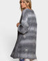 Woman wearing a long, patterned gray cardigan on a white background
