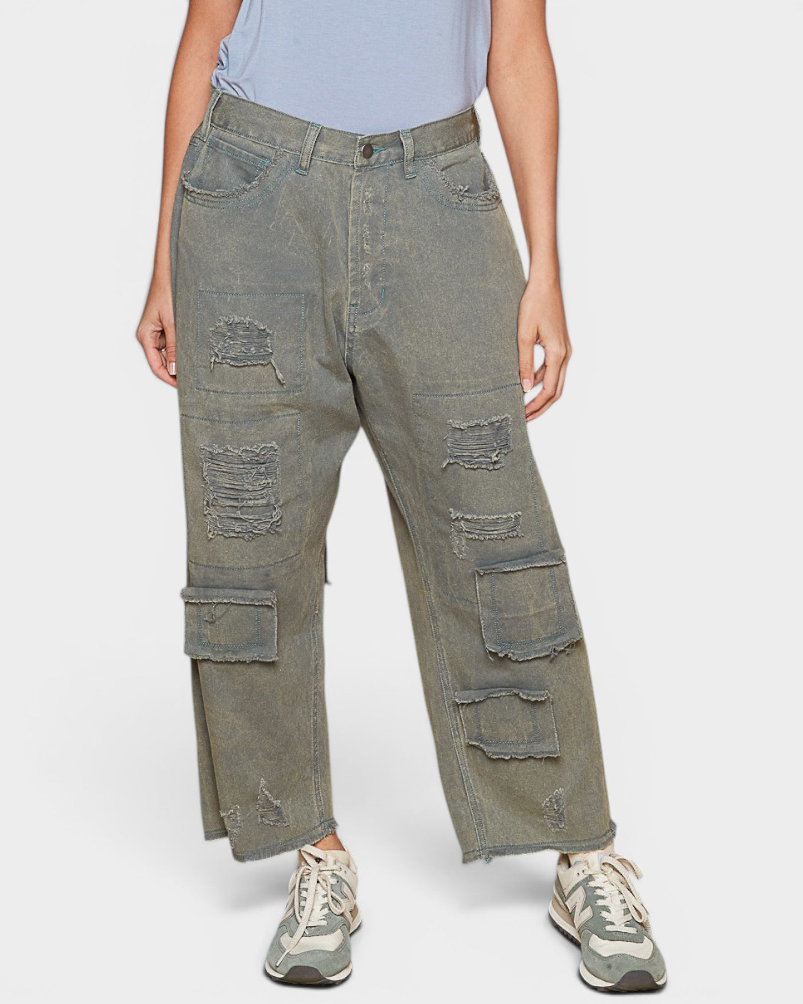 Person wearing distressed green cargo pants on a white background