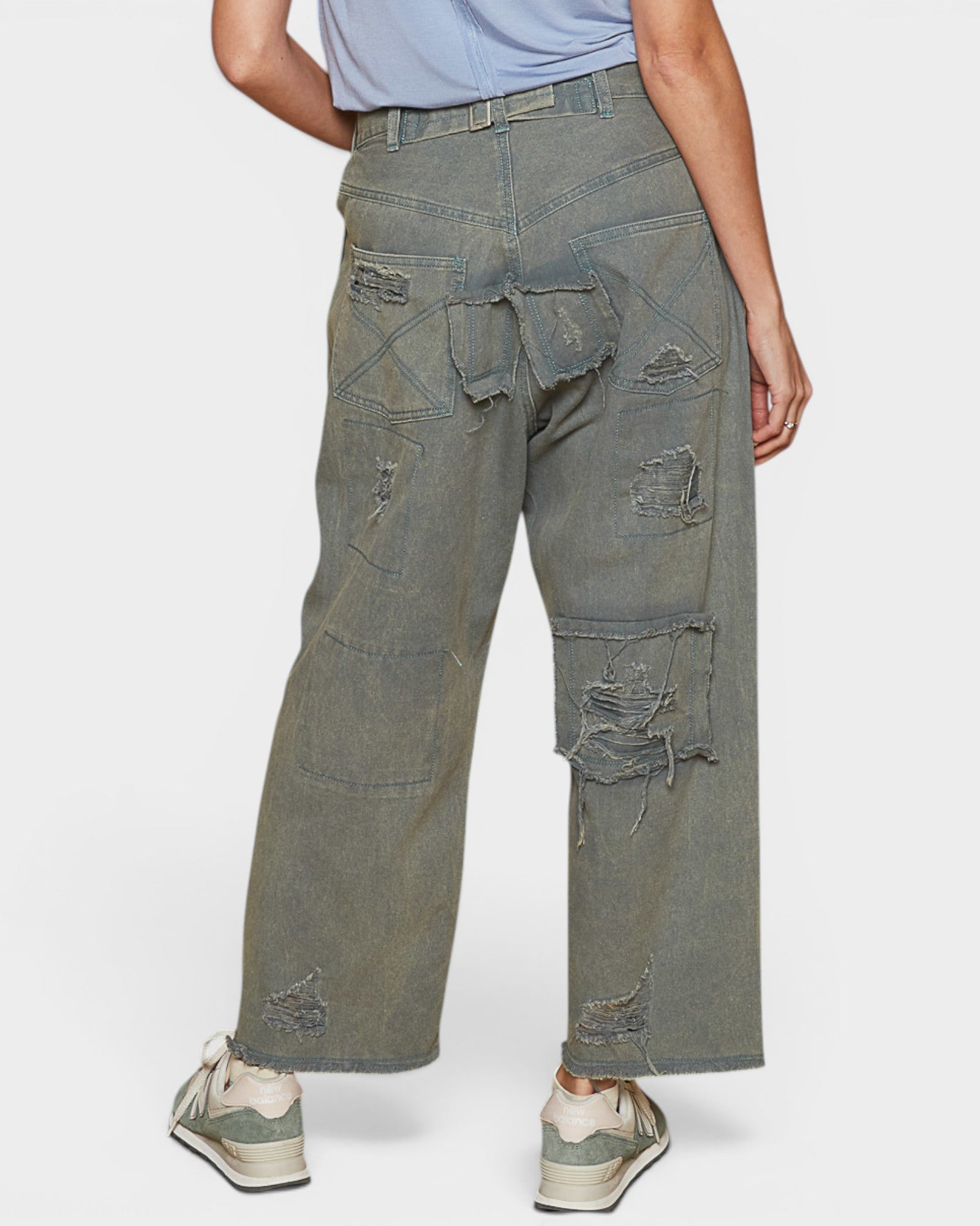 Person wearing distressed green cargo pants on a white background
