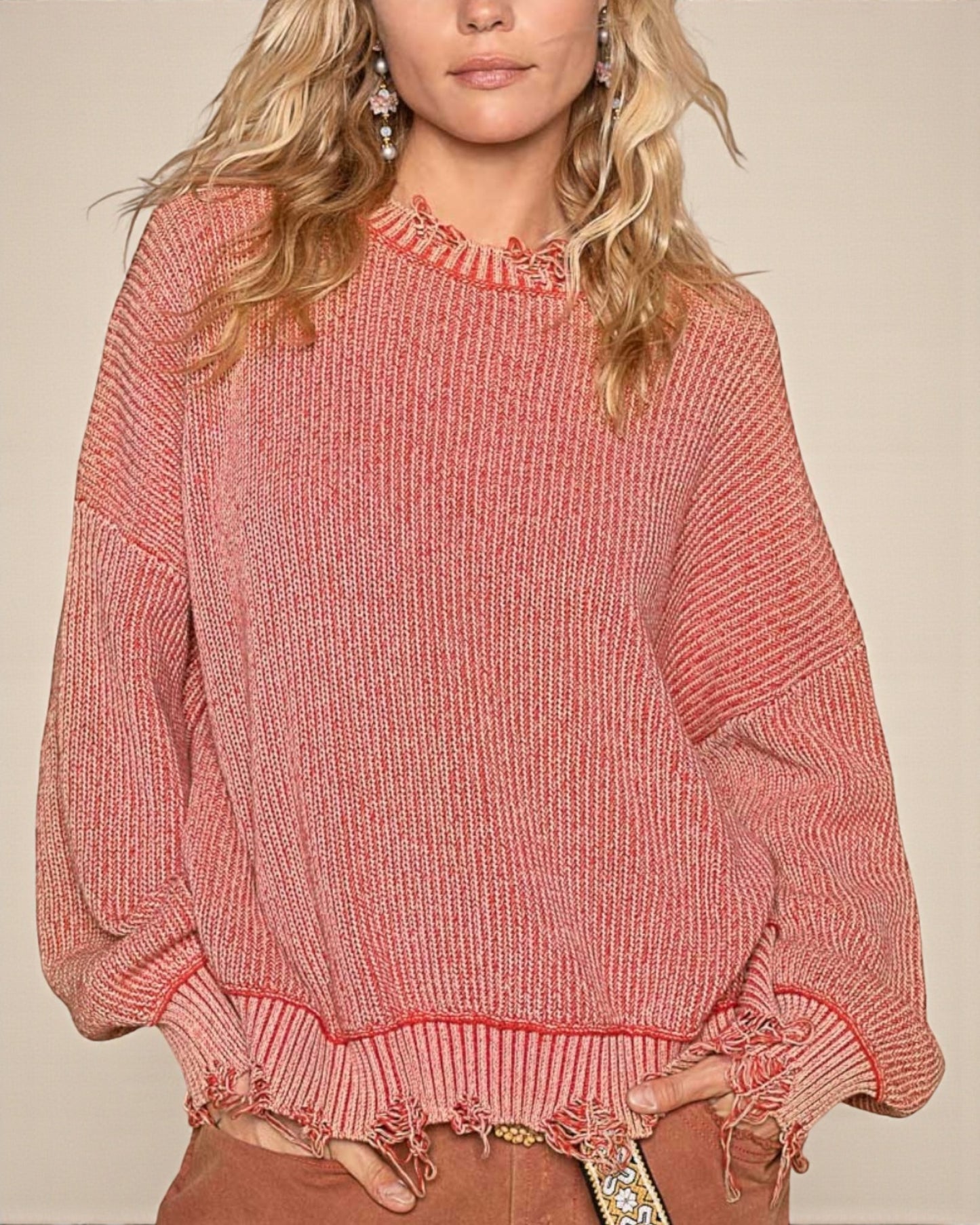 Person wearing a pink knitted sweater with fringe details on a beige background