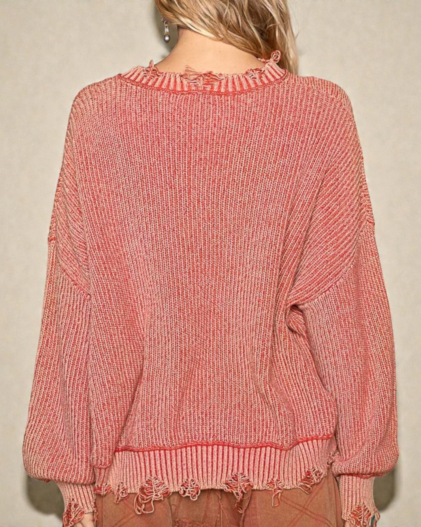 Pink sweater worn by a person against a beige background