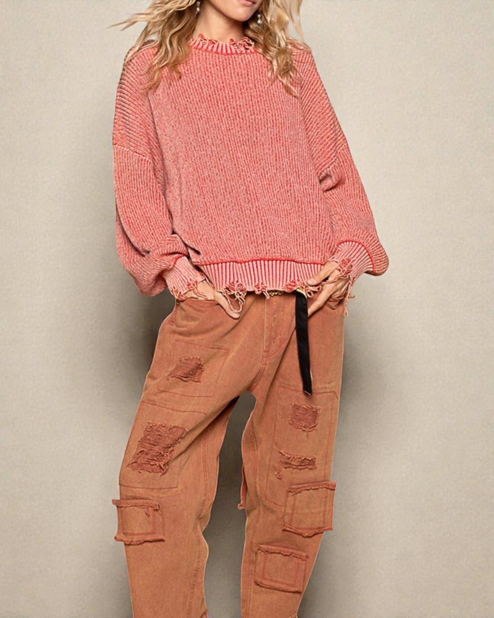 Person wearing a pink sweater and brown cargo pants against a beige background