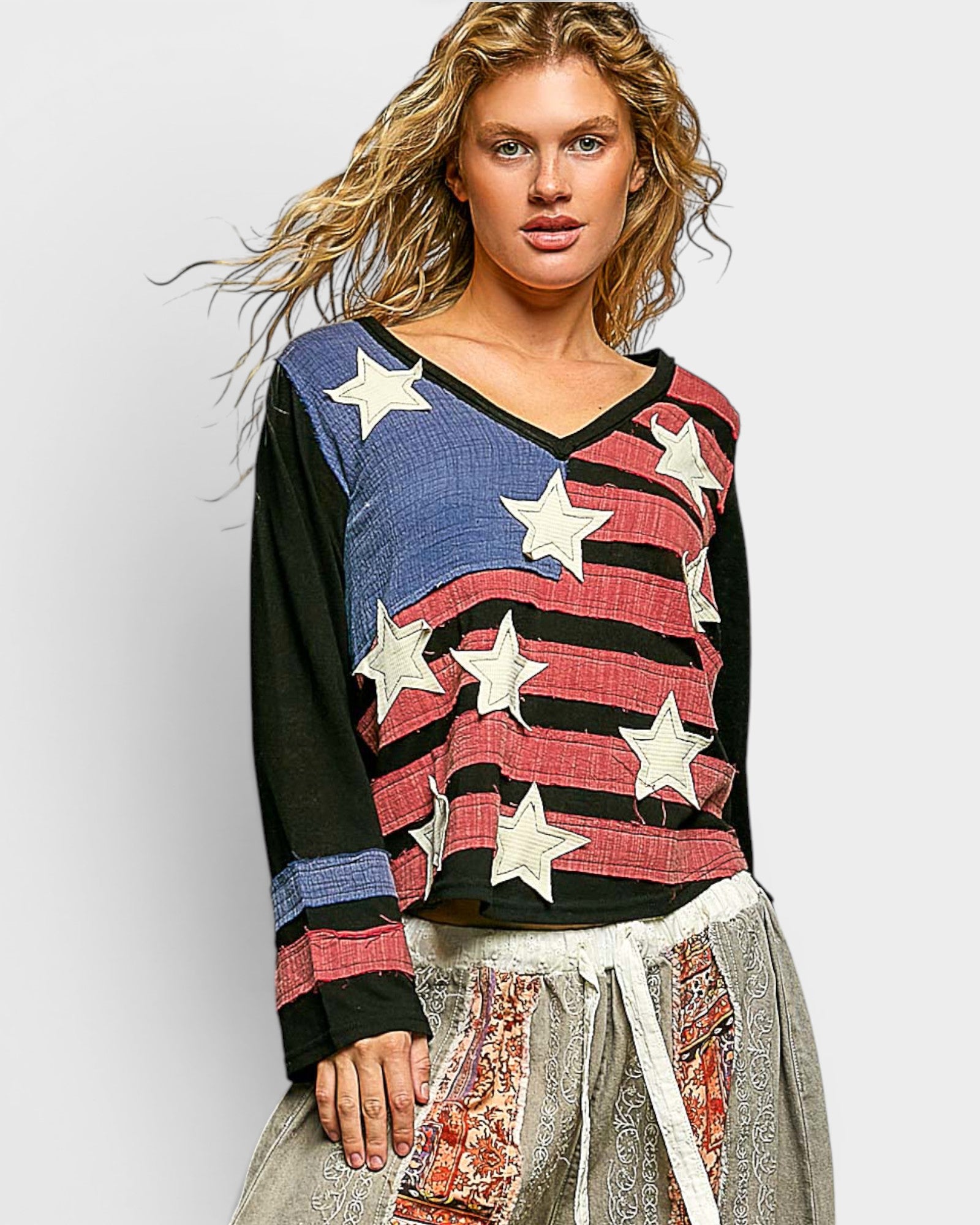 Woman wearing a colorful sweater with star patterns on a plain background