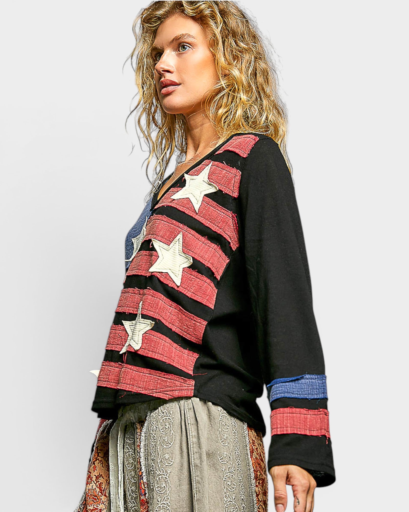 Woman wearing a black sweater with red and white star patterns on a plain background