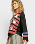 Woman wearing a black sweater with red and white star patterns on a plain background