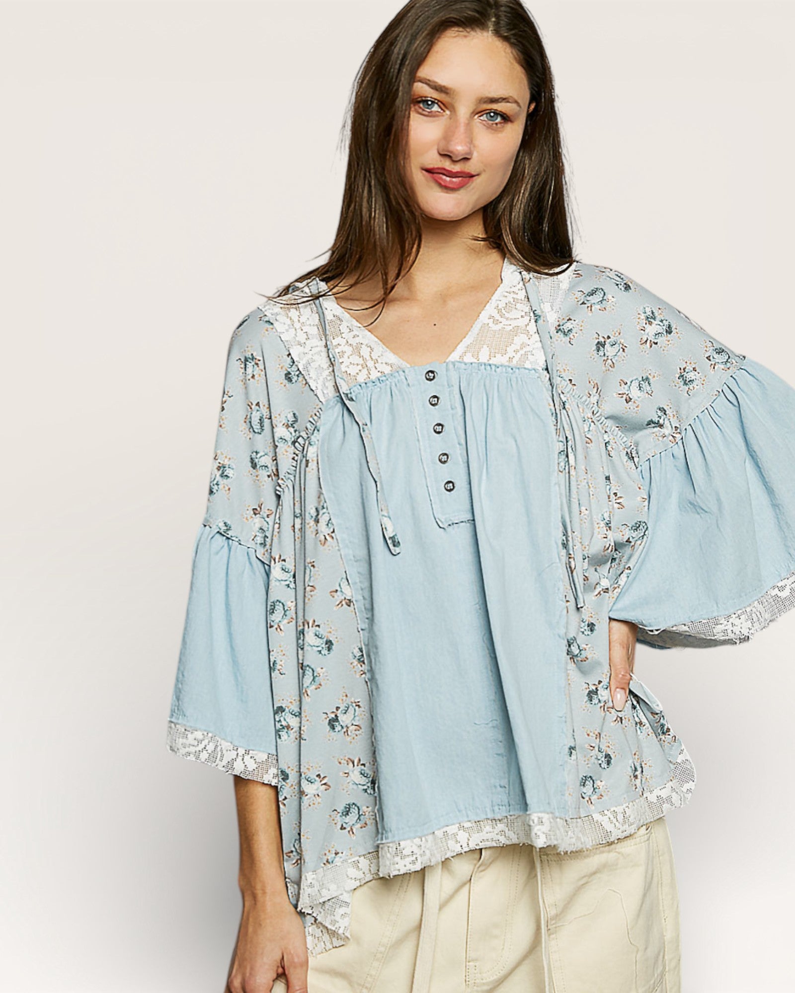 Woman wearing a light blue floral kimono over a matching blouse on a white background