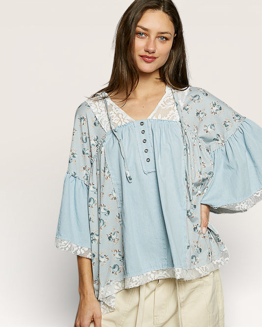 Woman wearing a light blue floral kimono over a matching blouse on a white background