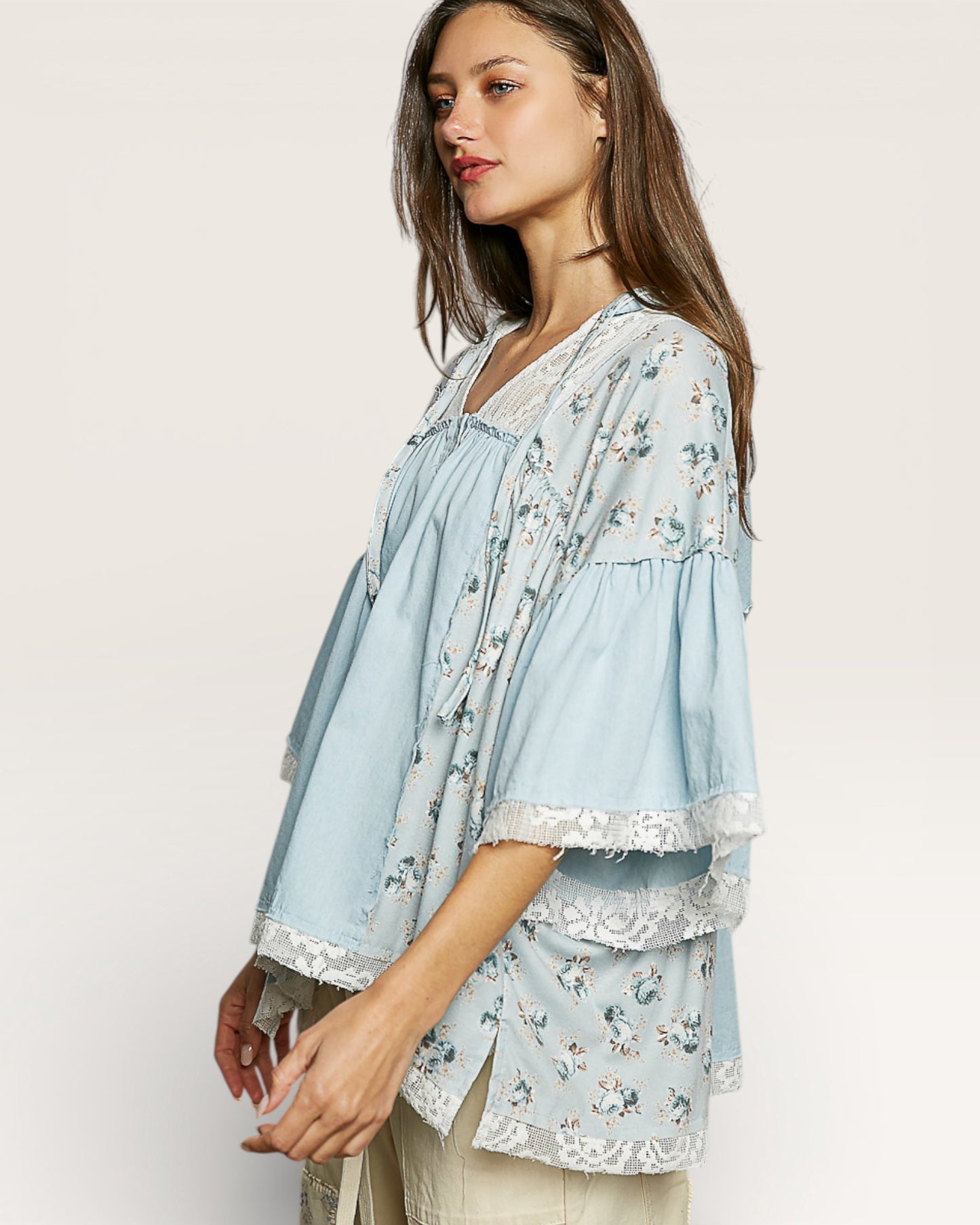Woman wearing a light blue floral blouse on a plain background