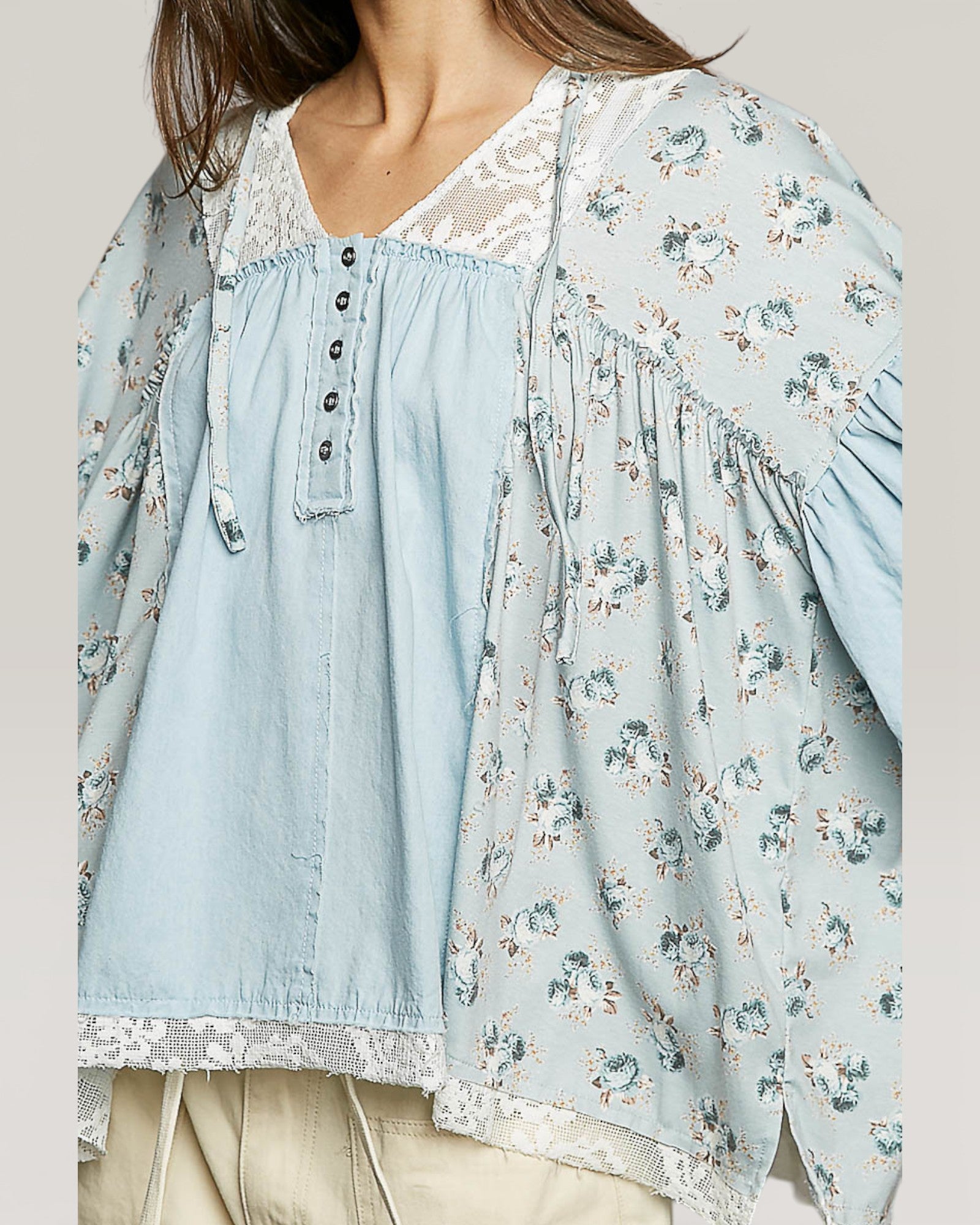 Light blue floral blouse with denim collar and cuffs on a neutral background