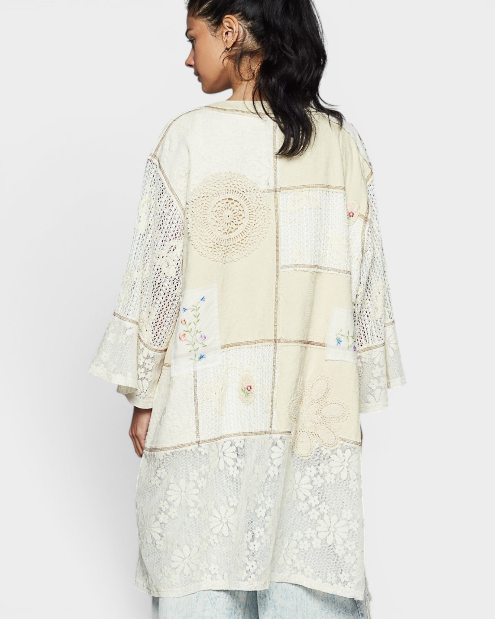 Woman wearing a cream-colored embroidered outfit on a white background