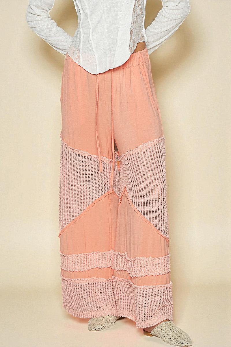 Person wearing a white blouse and peach-colored pants with a textured pattern on a beige background