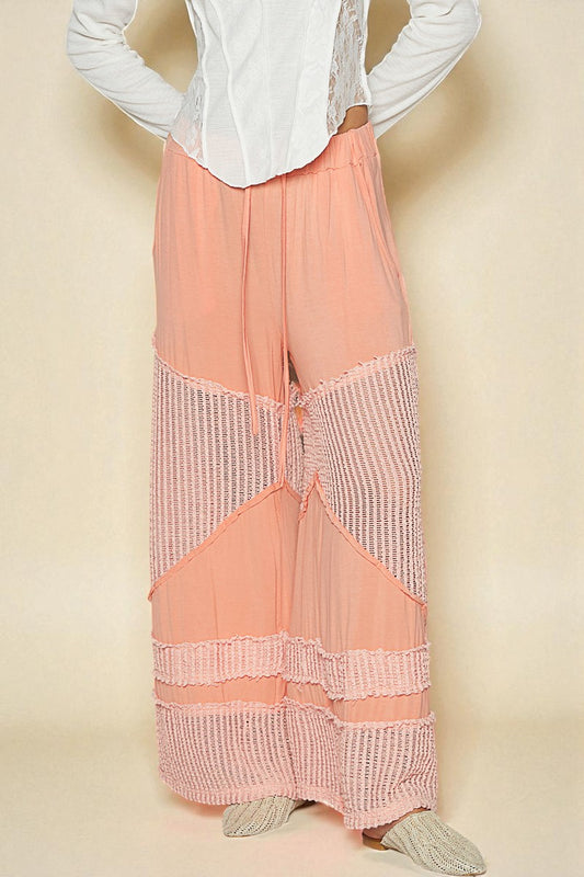 Person wearing a white blouse and peach-colored pants with a textured pattern on a beige background