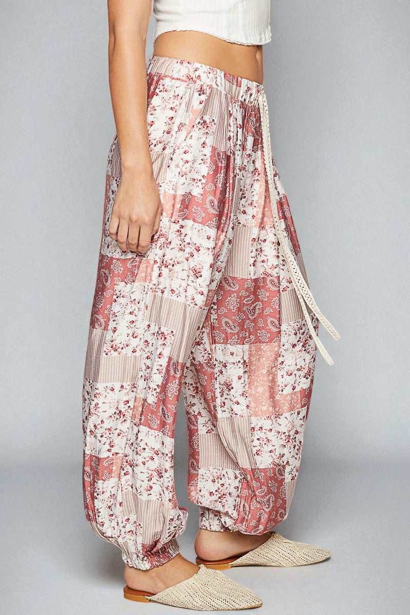 Floral patchwork pants worn by a person on a gray background