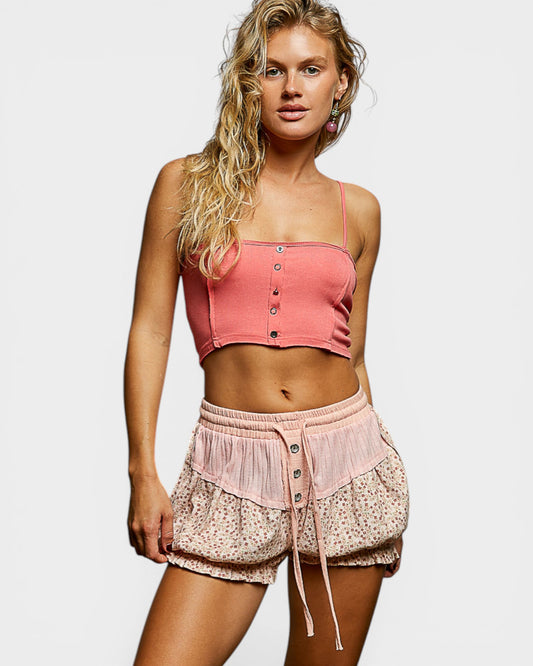 Woman wearing a pink crop top and shorts on a plain background