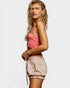 Woman wearing a pink top and patterned shorts on a white background