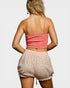 Person wearing a pink top and patterned shorts on a plain background