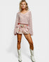 Woman wearing a pink knitted sweater and shorts with white cowboy boots on a white background