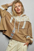 Person wearing a brown hoodie with lace details on a plain background