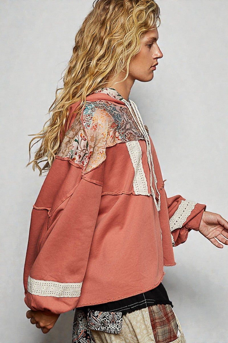 Person wearing a pink jacket with floral patterns on a plain background