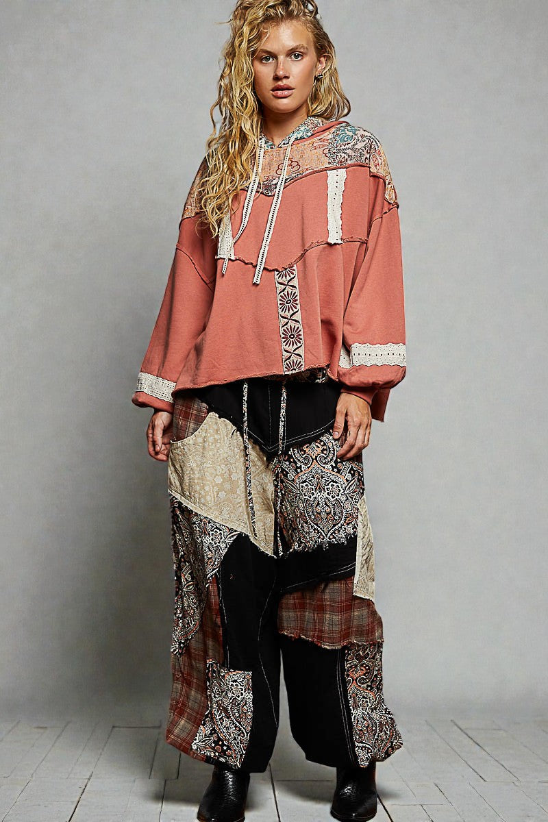 Person wearing a patterned outfit with a hood against a gray background