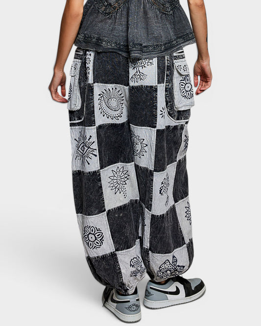 Person wearing patchwork denim pants with floral patterns on a white background