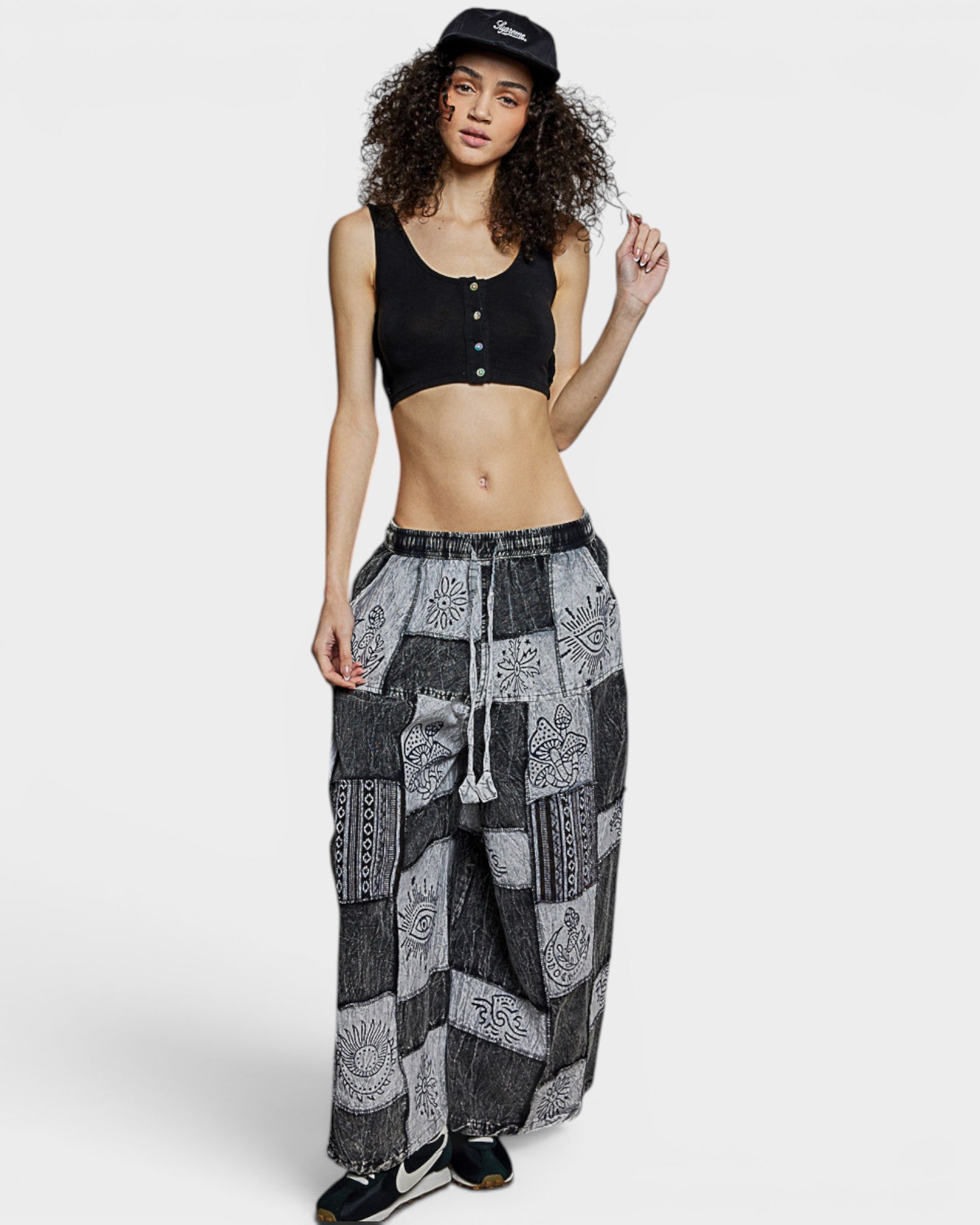 Woman wearing a black crop top and patterned pants on a white background