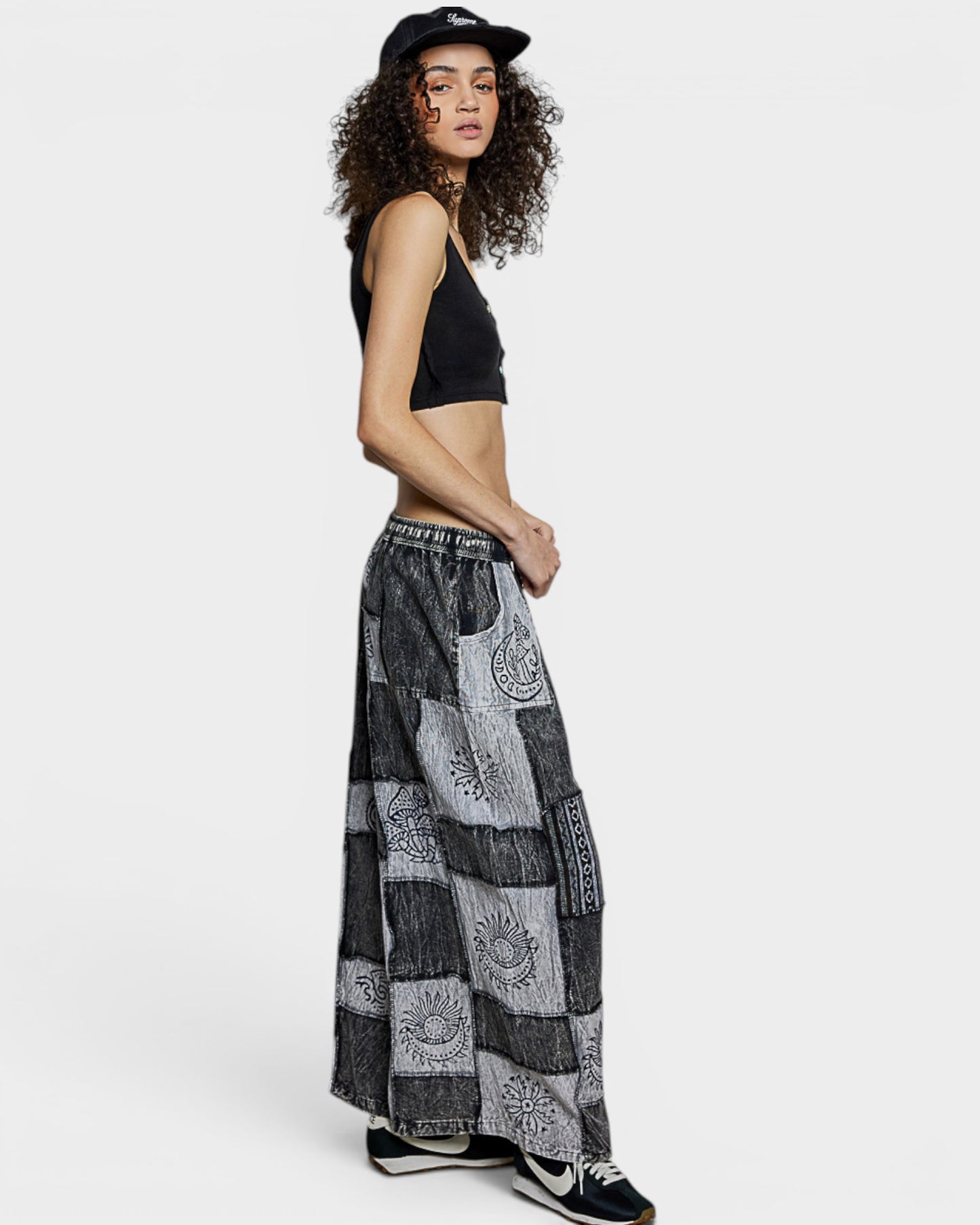 Woman wearing a black crop top and patterned long pants on a white background