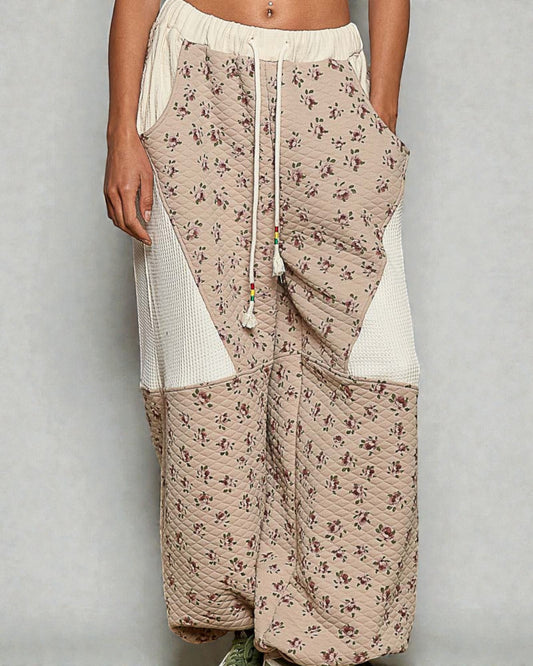 Beige floral-patterned pants with white accents on a plain background