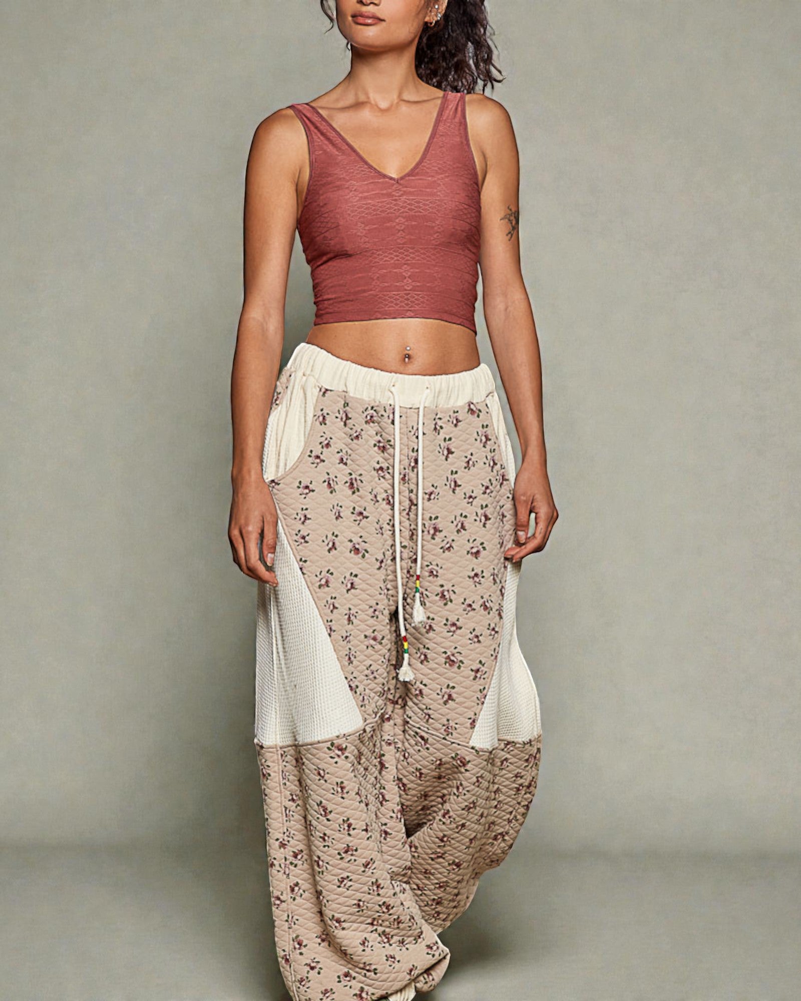 Woman wearing a red top and patterned pants against a neutral background