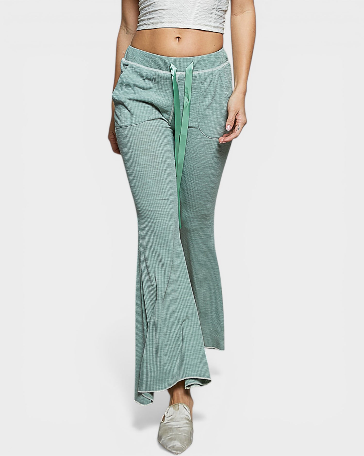 Person wearing light green drawstring pants on a white background