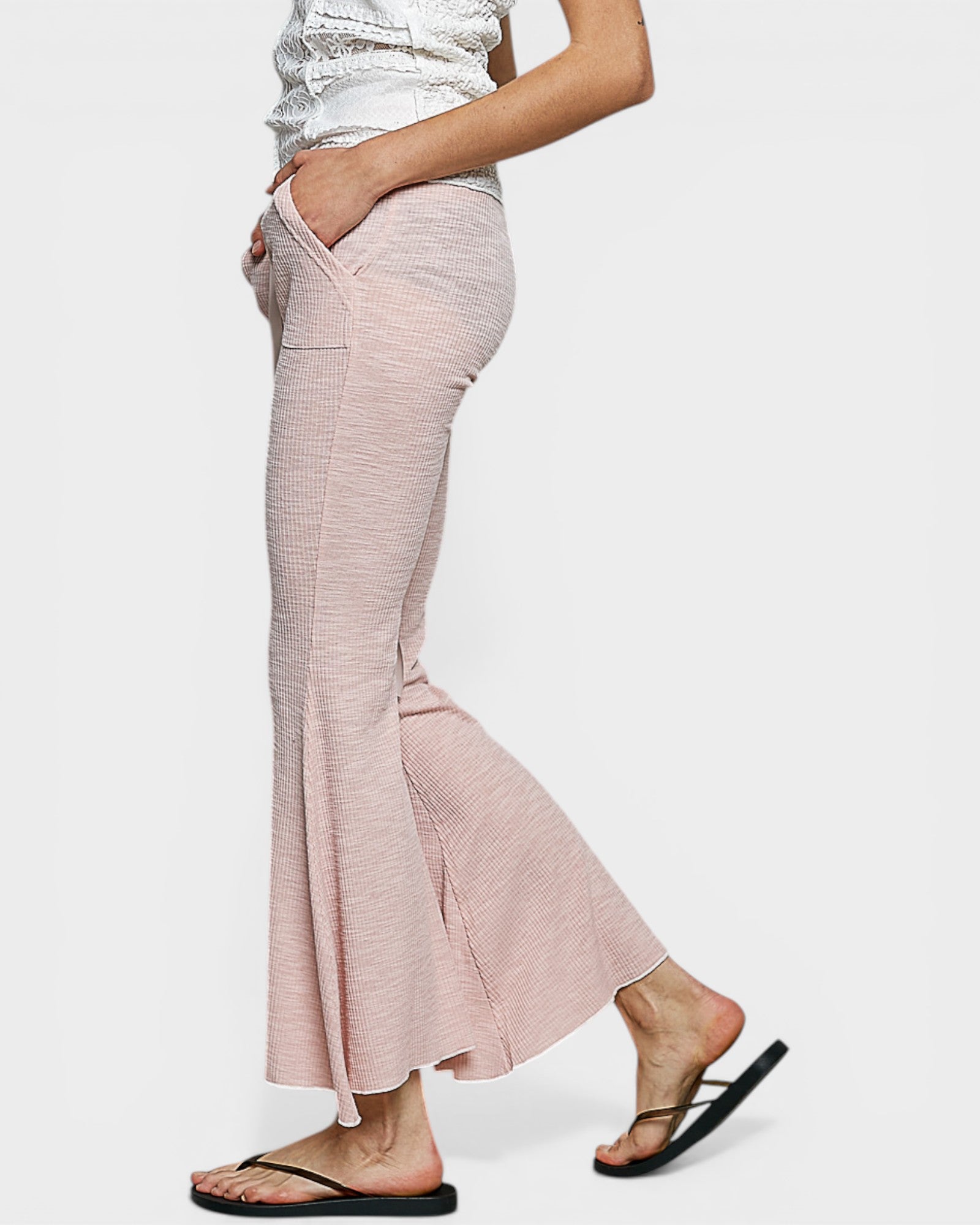 Person wearing light pink flared pants on a white background
