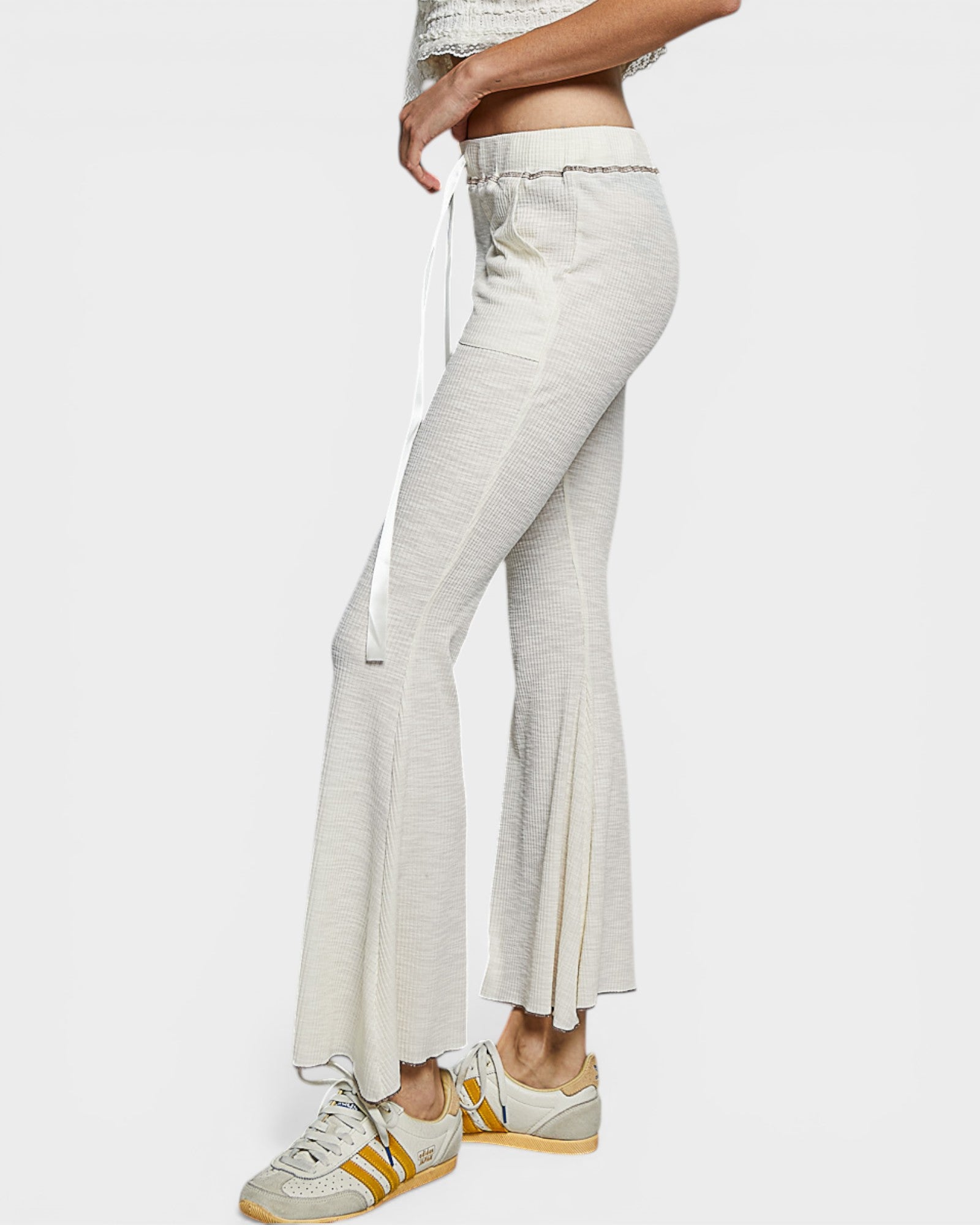 Light-colored flared pants worn by a person on a white background