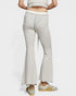 Person wearing light gray flared pants with a white top on a white background