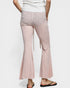 Person wearing light pink flared pants on a white background