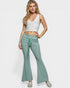 Woman wearing a white tank top and green flared pants on a white background