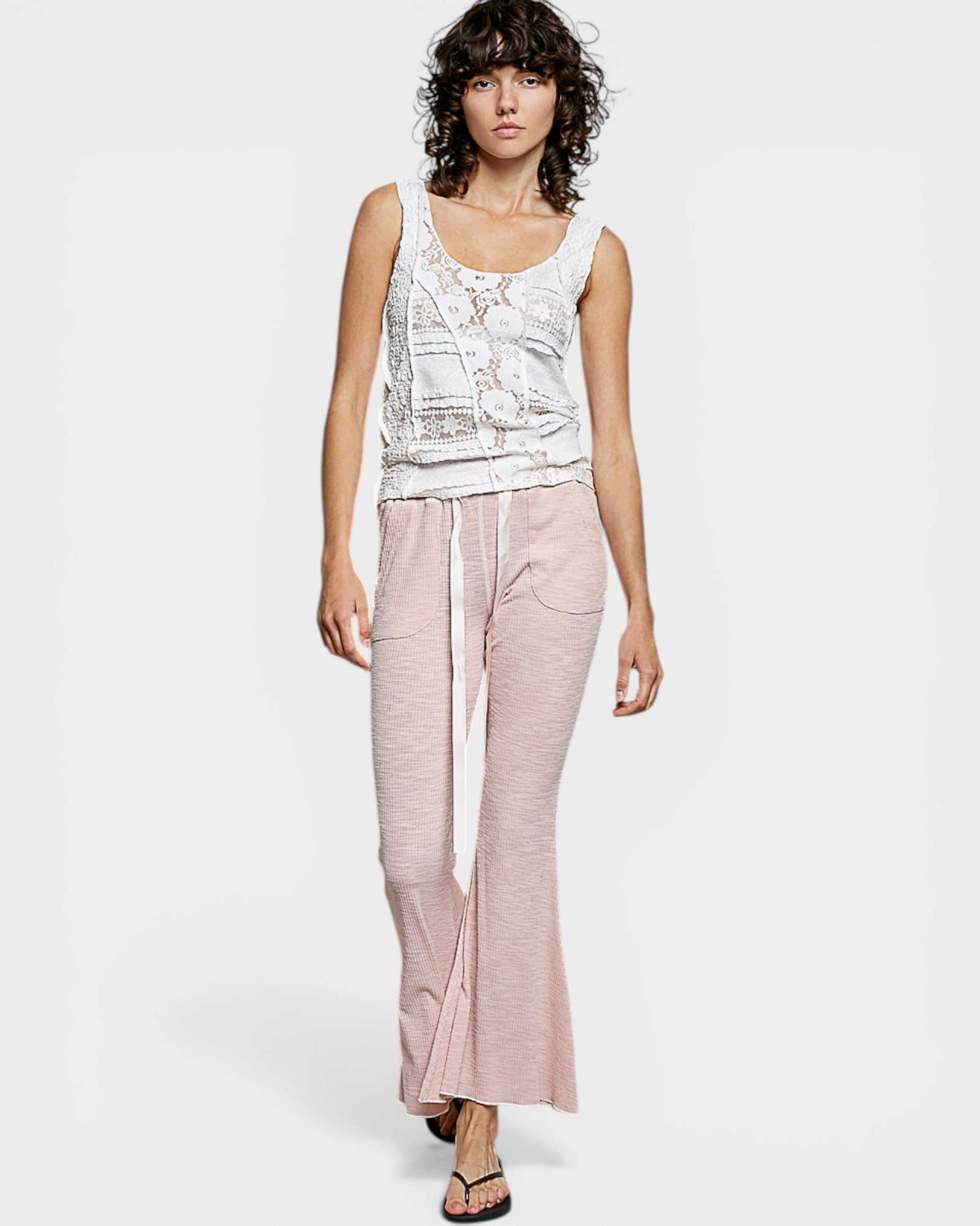 Woman wearing a sleeveless top and pink pants on a white background