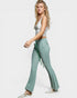 Woman wearing a light gray tank top and green flared pants on a white background