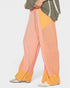 Color-blocked pants with orange, pink, and yellow sections on a white background