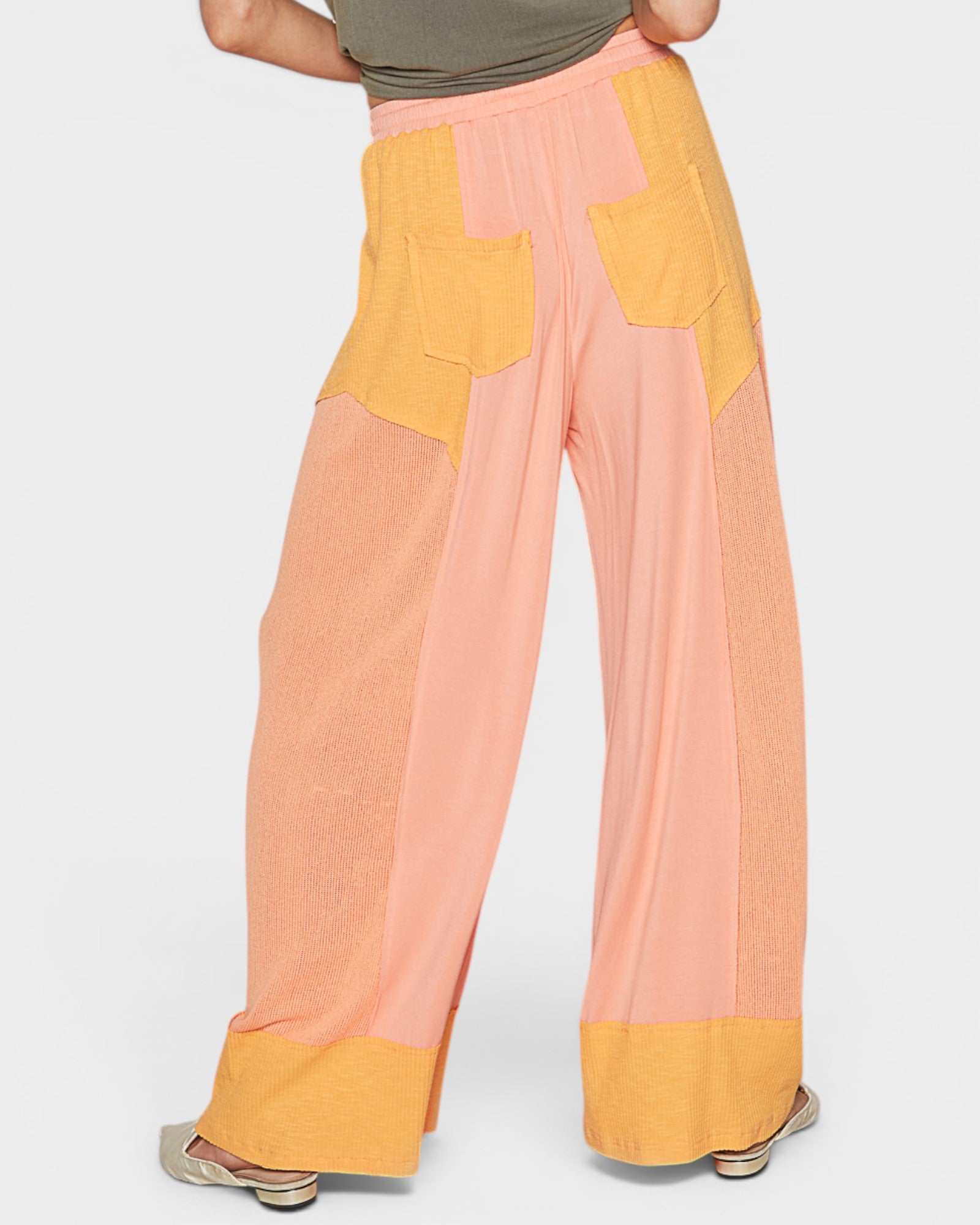 Color-blocked pants with pink and yellow sections on a white background