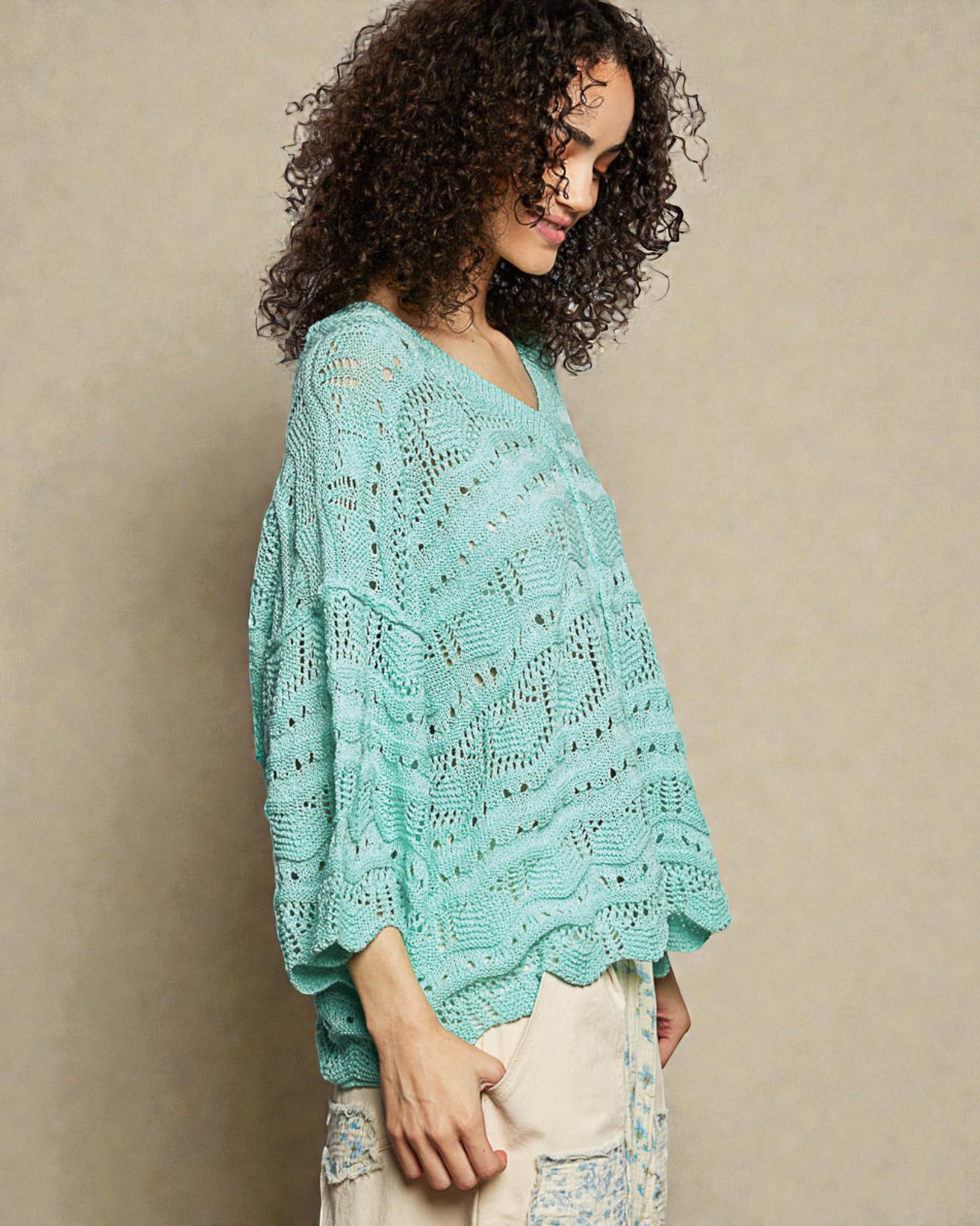 Woman wearing a light blue knitted poncho against a beige background