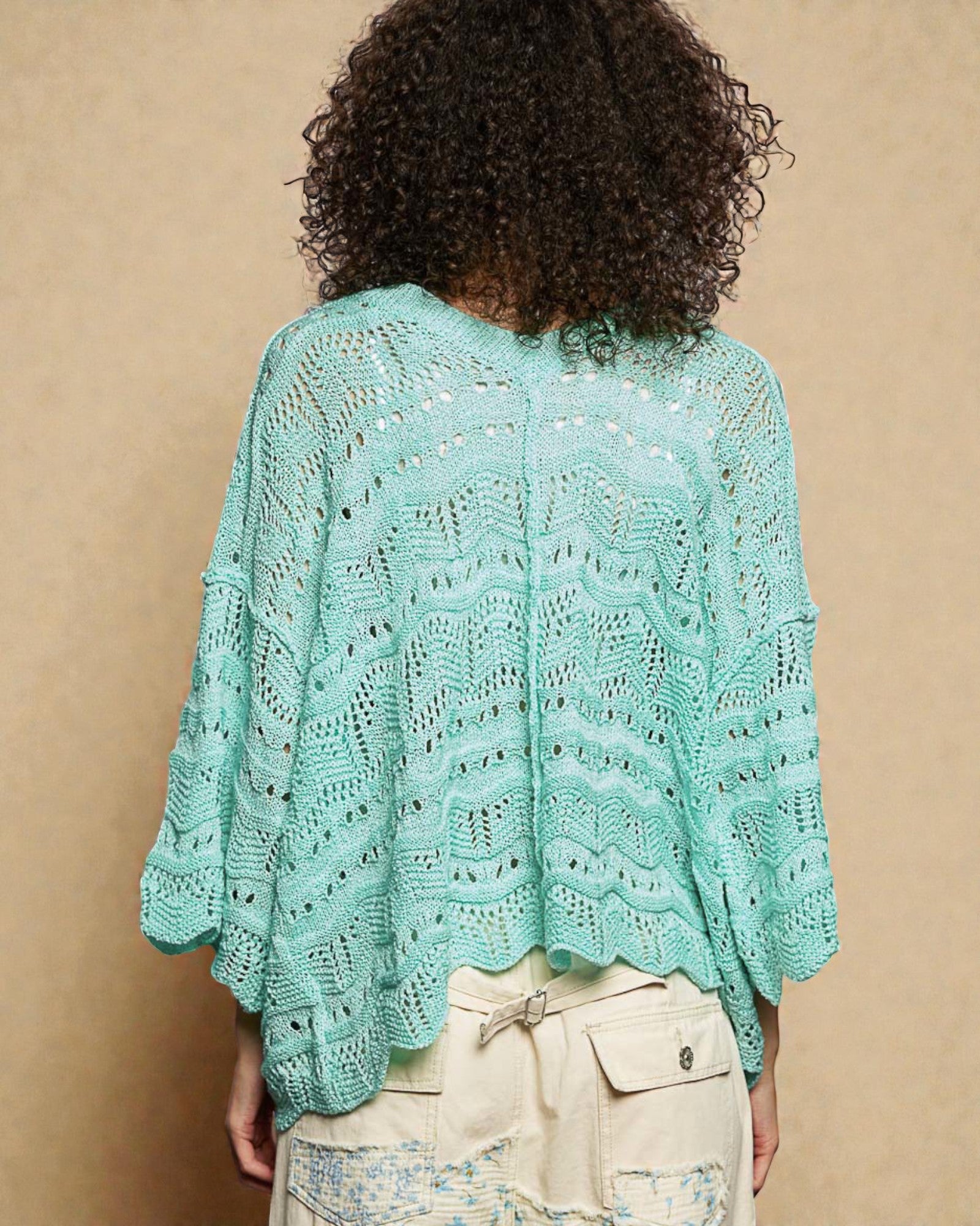 Person wearing a light blue knitted shawl against a beige background