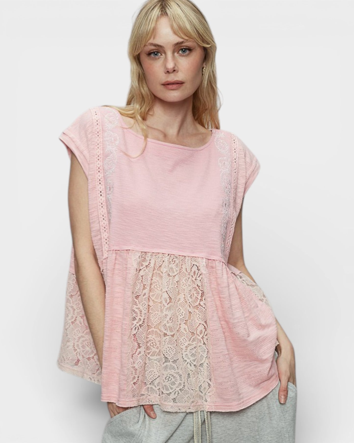 Woman wearing a pink lace top against a white background